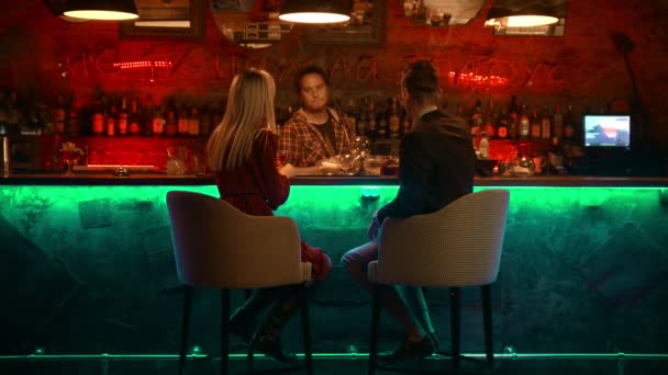 バーでデートをしている魔女のカップル-バーテンダーが立ってガラスをこすり、カップルと話をする — ストック動画