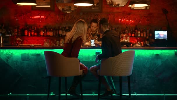 Un couple envoûtant ayant un rendez-vous dans le bar - barman faisant son travail et le couple regardant les photos au téléphone — Video