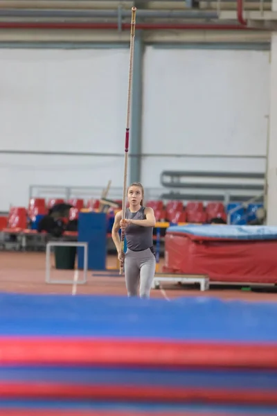 Skákání u tyče - mladá sportovkyně běžící s tyčí v rukou - vzhlíží k tyči, než skočí — Stock fotografie