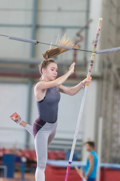 Biegun sklepienia w pomieszczeniach - młoda sportowa kobieta upadająca po skoku nad barierą — Zdjęcie stockowe