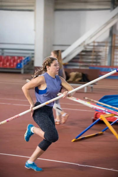 Pole vaulting indoors - young woman with pigtails running with a pole in the hands — 图库照片