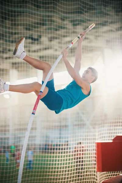 Biegun sklepienie w pomieszczeniach - młody człowiek fit skoków opierając się na słupie - stadion sportowy — Zdjęcie stockowe