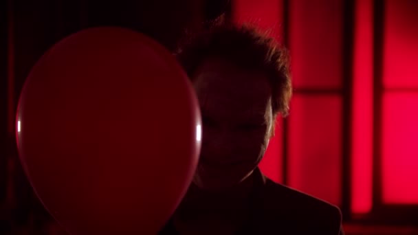Kırmızı balondan süzülen korkunç bir palyaço ve ürpertici bir gülümseme yanıp sönen ışık. — Stok video