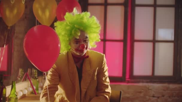 Усміхнений моторошний клоун у костюмі, що тримає червону кулю, передає м'яч глядачеві — стокове відео