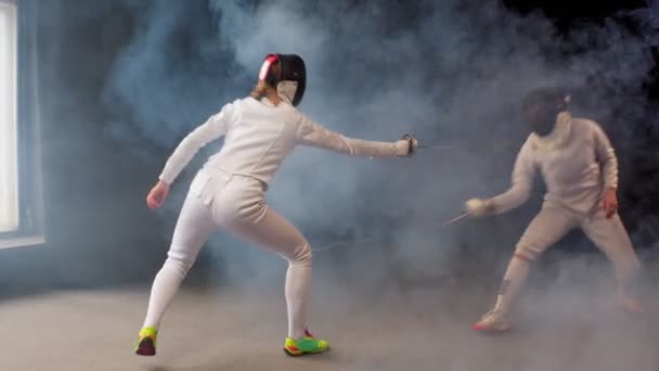 Две девушки-фехтовальщицы устроили в студии динамичный тренировочный поединок — стоковое видео