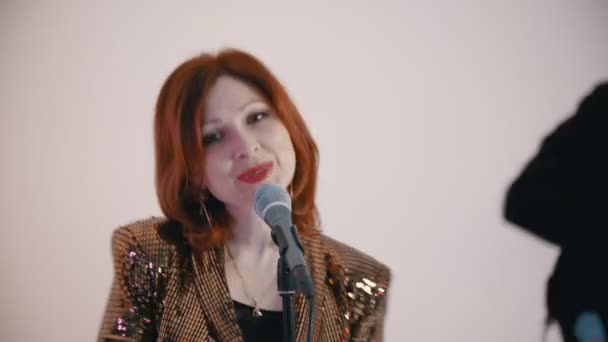 Kapak şarkısı çalan bir müzik grubu. Kızıl saçlı kadın tutkuyla şarkı söylüyor ve kameraya bakıyor. — Stok video