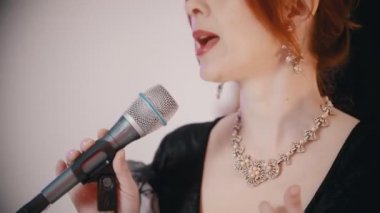 Bir müzik grubu şarkı söylüyor. Yetişkin bir kızıl kadın parlak stüdyoda şarkı söylüyor.