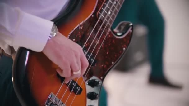 Un groupe de musique jouant une chanson en studio - un homme jouant de la guitare basse et une femme rousse chantant debout dans la robe bleue — Video