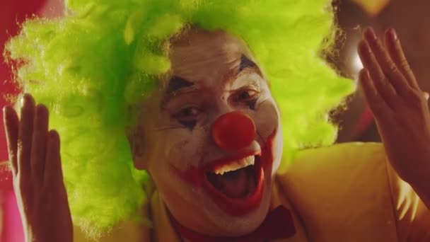 Een gekke lachende clown die zijn gezicht sluit met zijn handen en griezelige emoties uitvoert. — Stockvideo