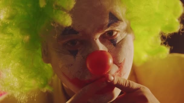 En clown med smulande färg på ansiktet läskigt leende sträcker ut munnen med fingrarna — Stockvideo