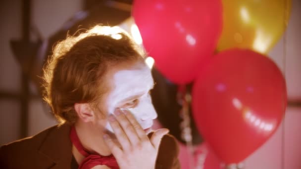 A man smearing white paint on his face in the dressing room - putting a fake smile on and continue looking at himself — Stock Video