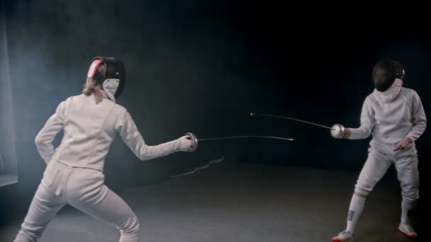 Treinamento de esgrima - duas mulheres tendo um duelo em trajes de proteção no estúdio — Vídeo de Stock