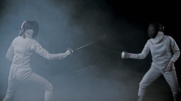 Fencing training - two young women having a duel in the smoky studio - poking in each other — Stock Video