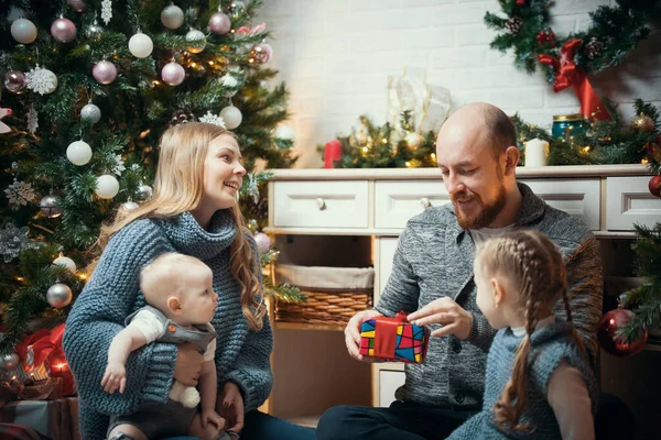 Concepto de Navidad - familia feliz sentada cerca del árbol y desempacando regalos — Foto de Stock