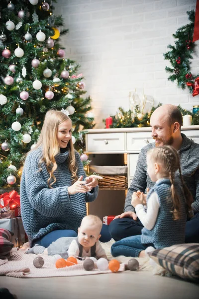 圣诞节的概念- -幸福的家庭坐在树旁 — 图库照片