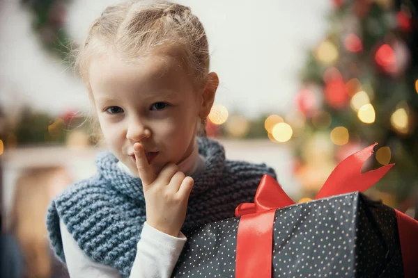 Concepto de Navidad: una niña presiona un dedo en los labios — Foto de Stock