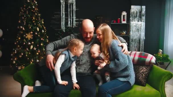 Концепция Рождества - счастливая семья, сидящая на диване и развлекающаяся — стоковое видео