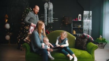 Noel konsepti - çocukları kanepede oturan bir anne - babam onlara gelip battaniyeyle örtüyor.