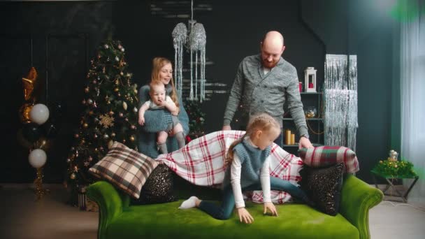 Karácsonyi koncepció - egy kislány ül egy split a kanapén, és a családja nézi őt