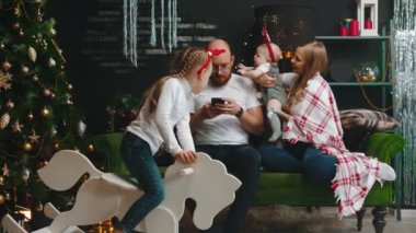 Noel aile kavramı - Baba telefonunda oturuyor - kızı telefonu alıyor ve bebek gözlüğünü çıkarıyor