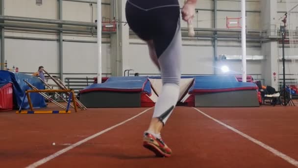 Pole hvælving indendørs - en ung kvinde i leggins løber op før hoppe – Stock-video