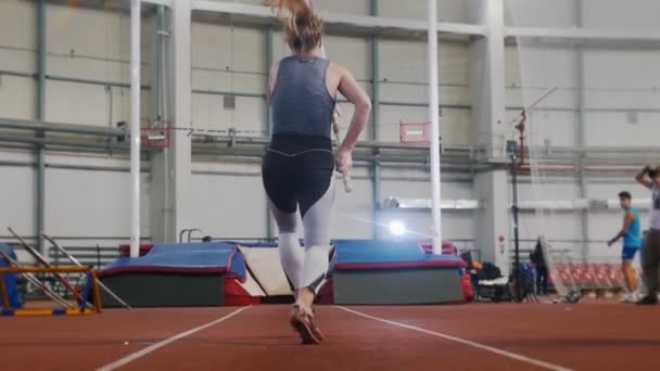 Pole vaulting inomhus - en ung kvinna med hästsvans som springer upp och hoppar över baren — Stockvideo