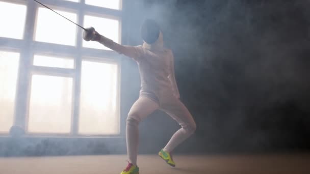 Молодая женщина фехтовальщик в белом защитном костюме выполняет основные движения нападения — стоковое видео