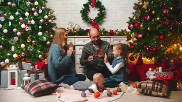 AÑO NUEVO - la familia en la atmósfera de Año Nuevo está jugando al pastel cerca del árbol de Navidad — Vídeos de Stock