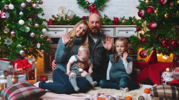 Nový rok - rodina sedí spolu s úsměvem a mává do kamery — Stock video