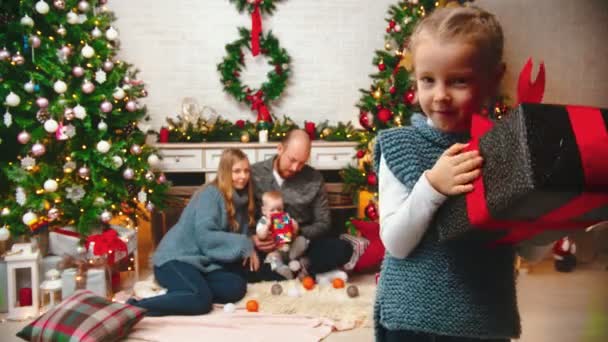 Neues Jahr - Tochter schüttelt ein Weihnachtsgeschenk — Stockvideo