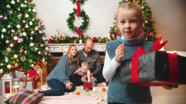 Nowy Rok - córka potrząsa prezentem i przykłada palec do ust — Wideo stockowe
