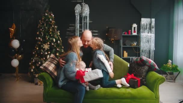 Christmas concept - wife and daughter kiss the man and husband in the cheeks and a girl hugs her dad — Stock Video