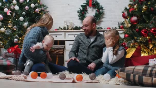 Año Nuevo - los padres le están pidiendo a su hija que cierre los ojos y le dé un regalo — Vídeo de stock