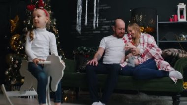 Yeni yıl - aile beyaz tişörtlerle battaniyenin altında oturuyor ve hter oyuncak ata biniyor