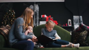 Yılbaşı - çocuklu anne kanepede oturup kitap okuyor ve babam hediyelerle geliyor.