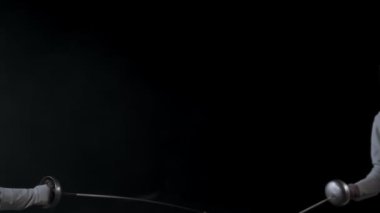 Stüdyoda eskrim eğitimi. Beyaz kostümlü iki genç kadın düello yapıyor.