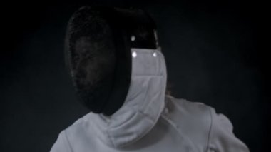 Fencing training in the studio - young woman in protective helmet having a duel