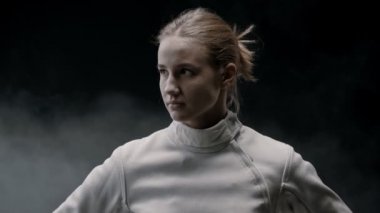 Dumanlı stüdyoda güzel bir kadın eskrimci.