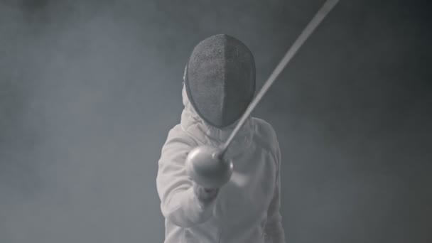 Обучение фехтованию в темной студии - молодая женщина фехтование в дыму — стоковое видео