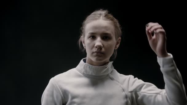 A young attractive woman fencer lets her hair down and shakes her head — ストック動画