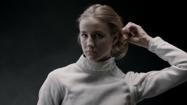 A young pretty woman fencer lets her hair down and shakes her head — ストック動画