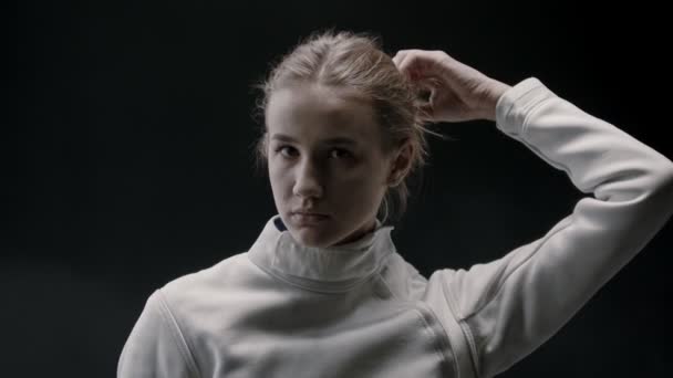 A young pretty woman fencer lets her blonde hair down and shakes her head — Stock Video