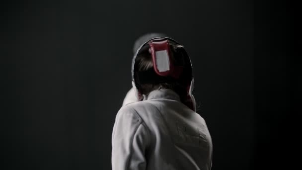 A fencing training in the dark studio - two women in protective suits having a duel — ストック動画