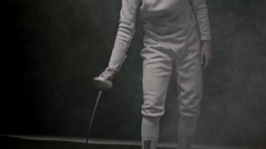 Genç bir eskrimci kadın kılıcını fırlatıyor ve onu yakalıyor.