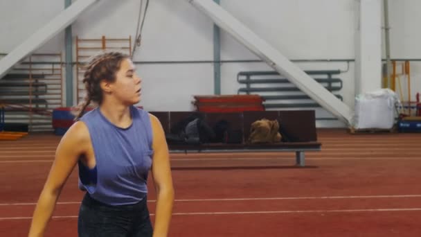 Stabhochspringen drinnen - junge Frau mit Zöpfen bereitet sich auf den Sprung vor - hochlaufen - über die Stange springen — Stockvideo