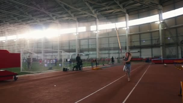 Entrenamiento de bóveda de poste - una joven con cola de caballo corriendo y saltando sobre la barra - toca la barra — Vídeos de Stock