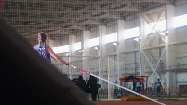 Bóveda de poste en el estadio interior - mujer joven con coletas levanta el poste y comienza a correr — Vídeo de stock