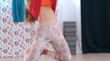 Yoga yapmak için hamakta baş aşağı asılı duran genç bir kadın.