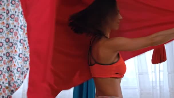 Una mujer atlética jugando con la hamaca roja para el yoga - se envuelve en un paño — Vídeo de stock