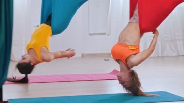 Havadan yoga hamağında dönen iki kadın.